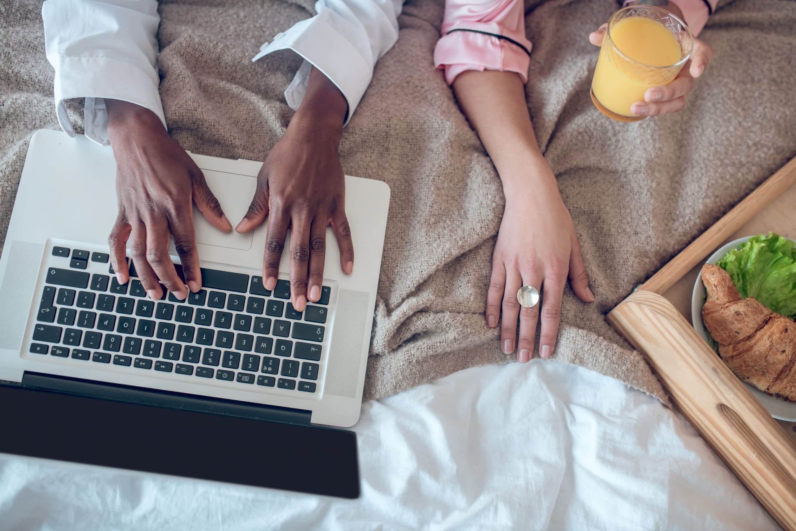 Couple sitting in a hotel bed, writing Kruger National Park accommodation reviews online