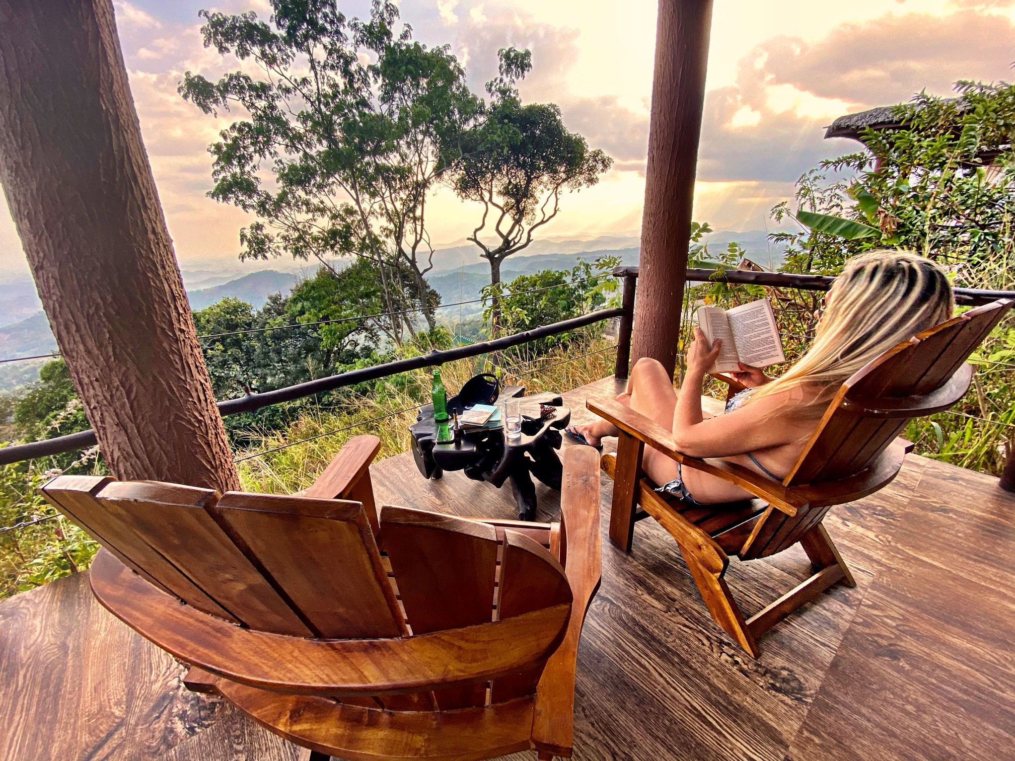A women in swimming attire, relaxing outside her Kruger chalet with a book