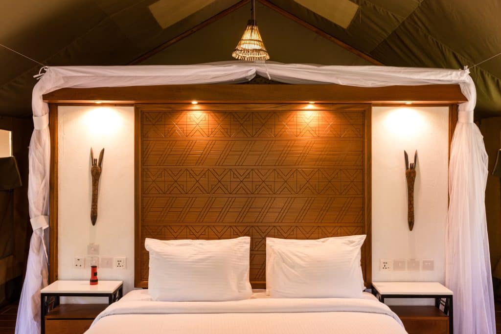 A close up of the head of a brightly lit bed covered in white linen in Kruger accommodation.