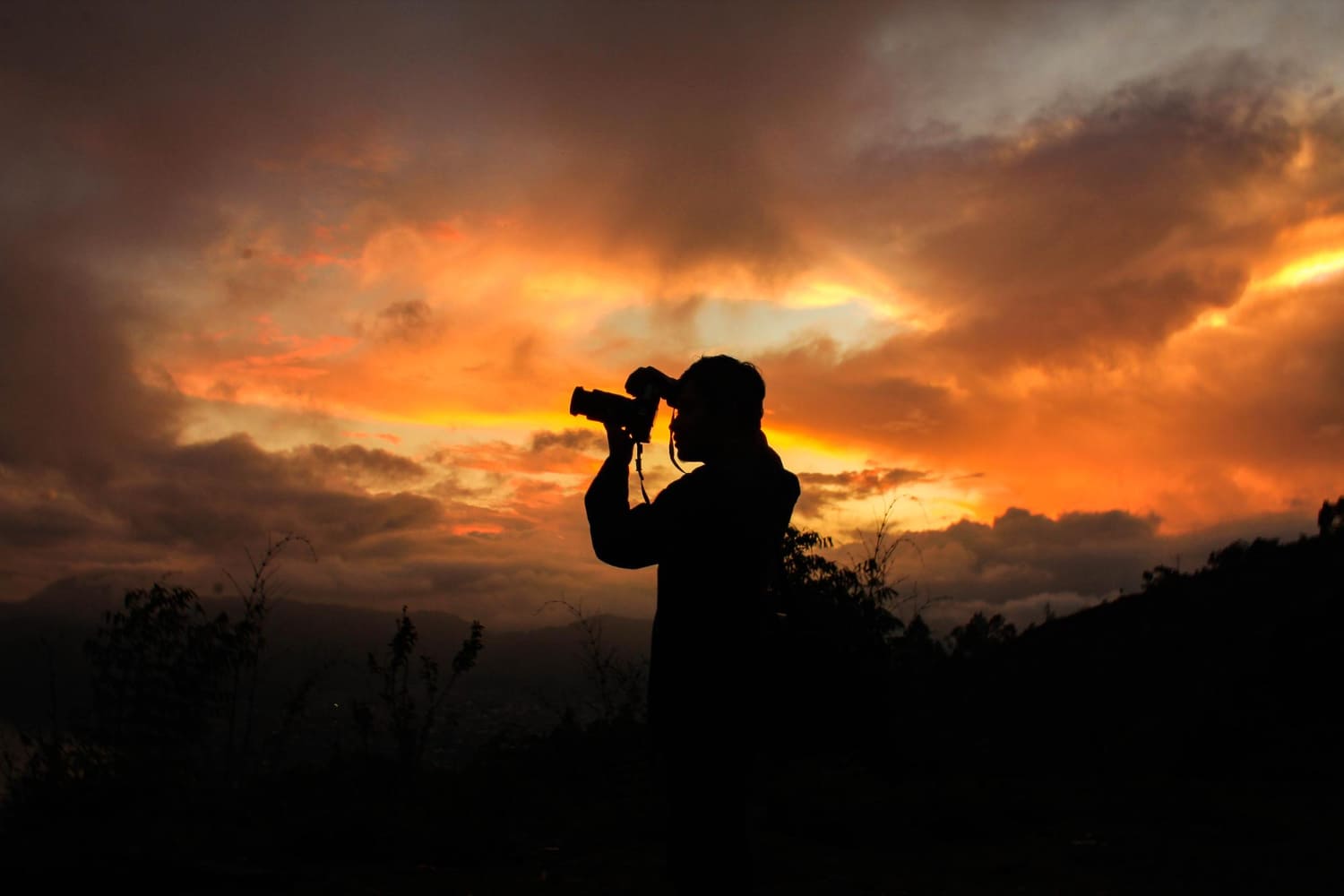 Silhouette of person photographing the sunset