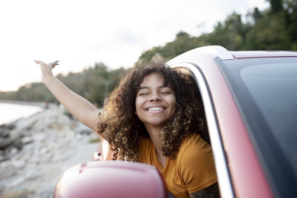 A young lady hanging out the window of a car on a Cape Town to Kruger road trip
