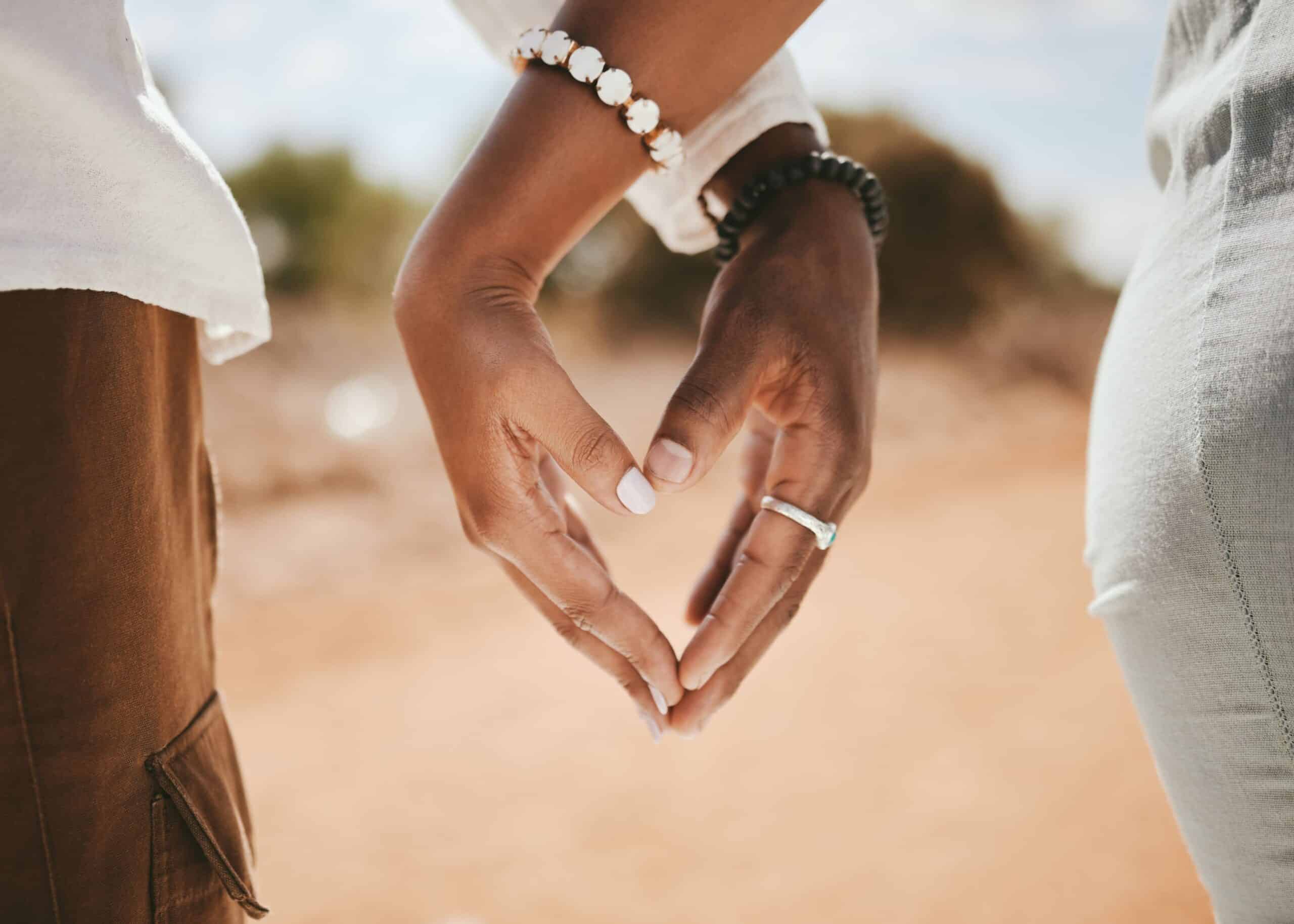 A couple with finger tips touching in a heart shape while on a romantic safari