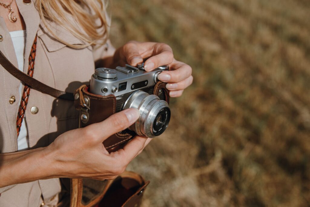 A closeup of a lady adjusting a camera’s focus while doing some outdoor photography