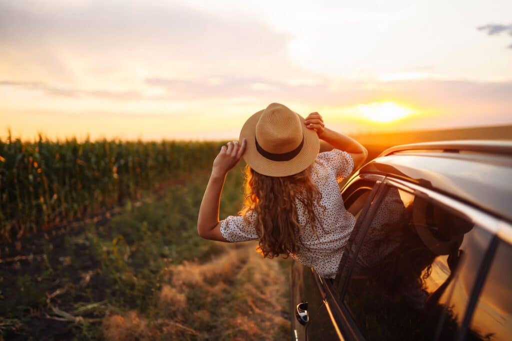 A young lady hanging out of a car’s passenger window on a Joburg to Kruger Park road trip