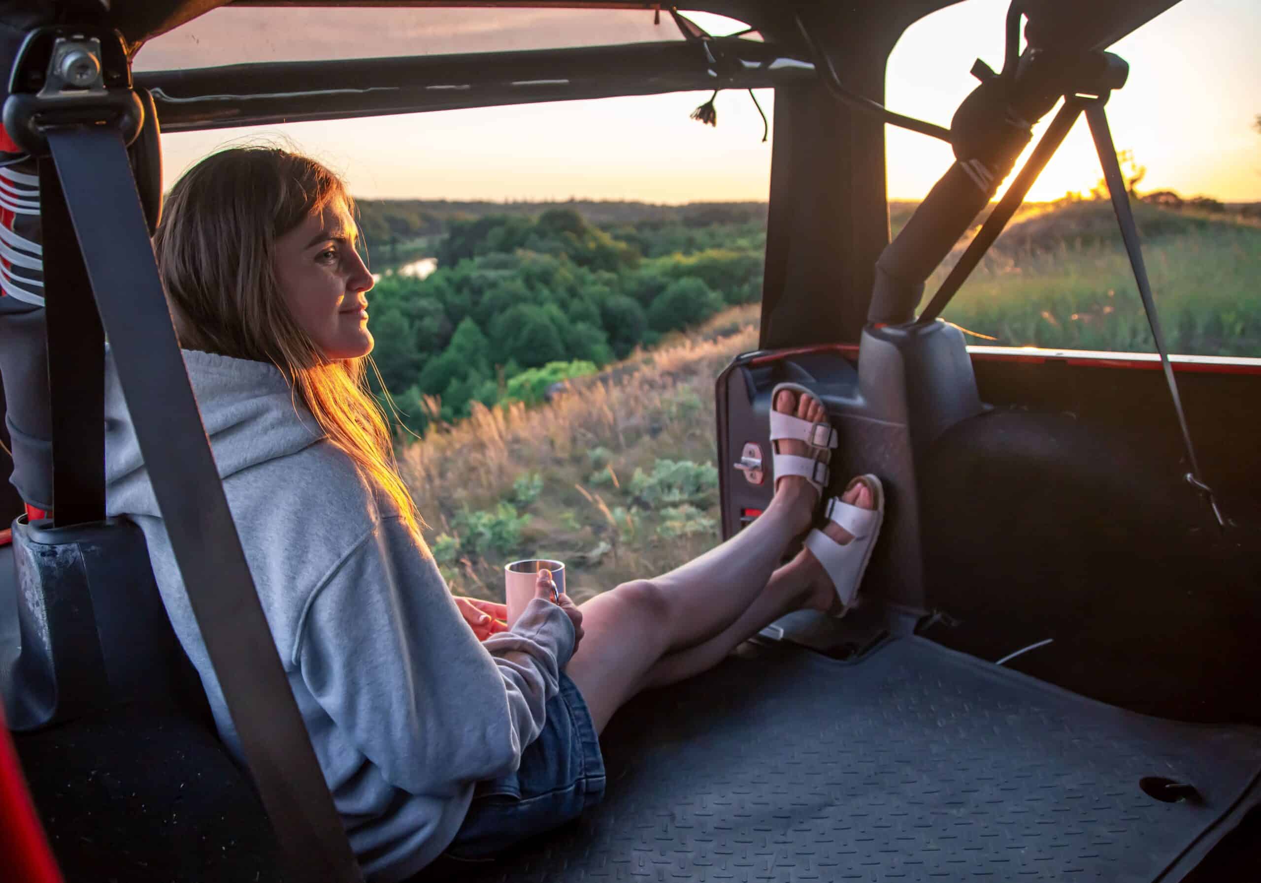 A young lady drinking coffee from a vehicle on a Kruger Park self drive safari