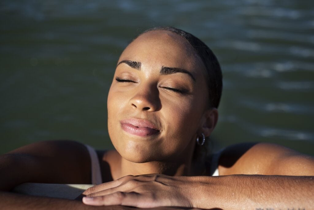 A woman basking in the sun from a swimming pool while holidaying at self-catering accommodation